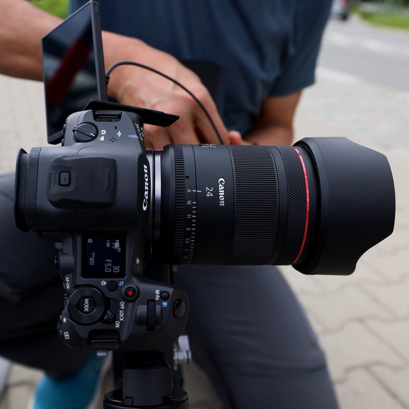 Canon RF 24mm F1.4L VCM Objektiv Mann, der ein Foto von einer Kamera und einem Objektiv mit einem Objektiv knipst, das auf einem Stativ befestigt ist