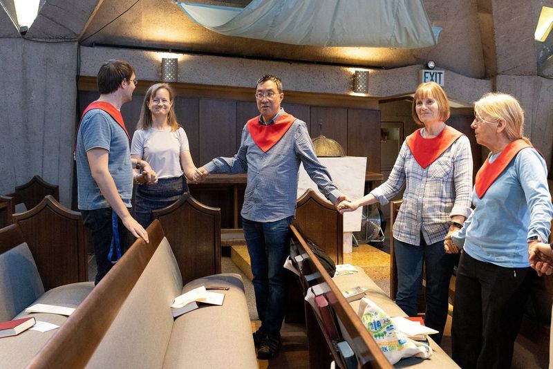 Five congregants with red neckties stand holding hands at church. Photo by Laura Morton.