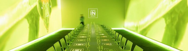 A long dining table, bathed in green light with the Dinner in Motion logos projected onto it.
