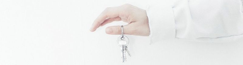 An outstretched arm and hand, dangling a set of keys from the thumb.