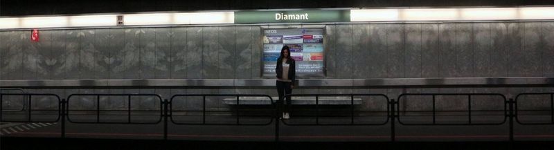 A young woman stands alone on a train platform. 