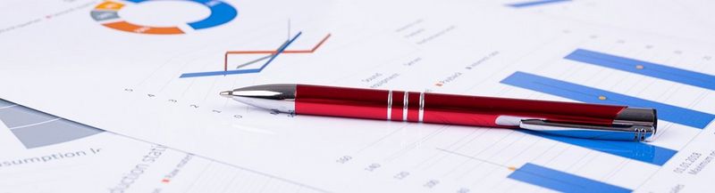 A pen, sat across papers printed with charts.