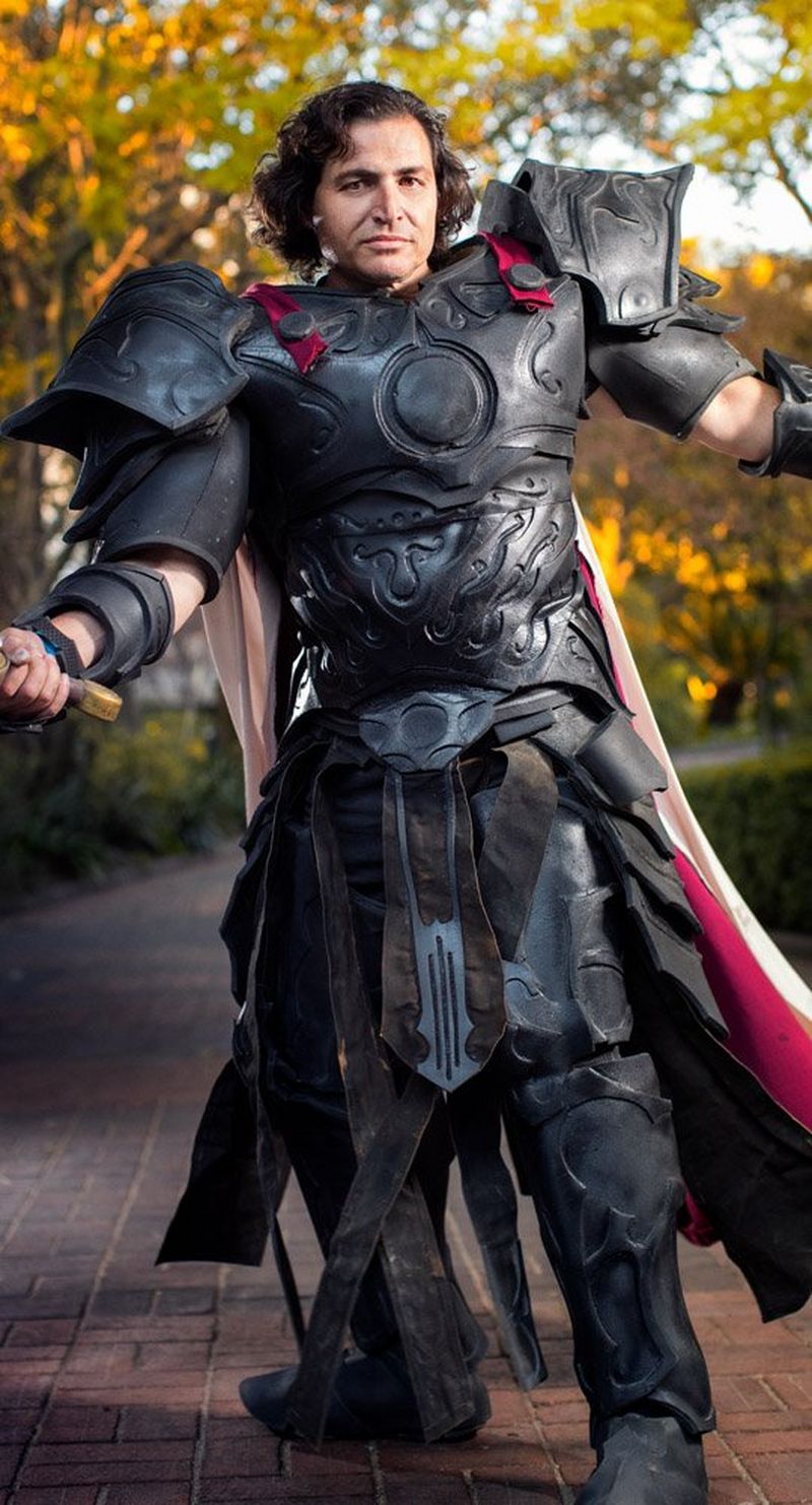 A man in cosplay costume poses in a park.