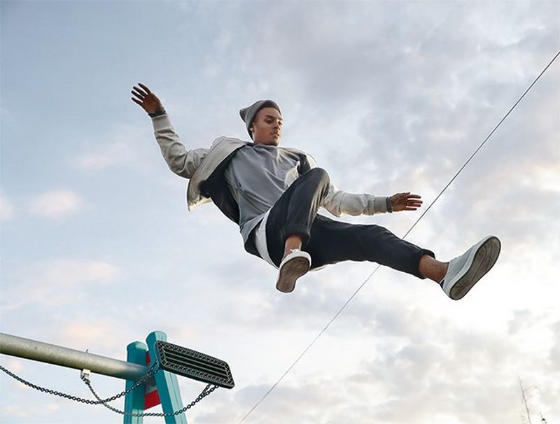 A man leaps over the camera under a blue sky.
