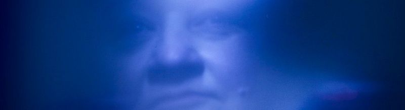 A clouded and slightly blurred image, all in blue. Through it, the features of a woman’s face can be seen. © Daphne Wageman