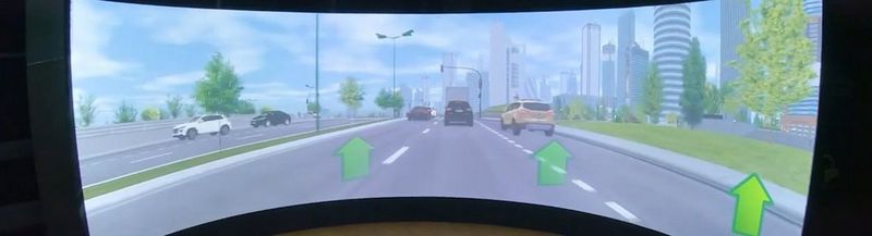 A wide screen depicting a highway with five cars and office buildings running alongside the road to the right.