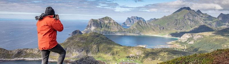 Photographer Richard Walch looks out over a coastline, taking a photo with his Canon camera.