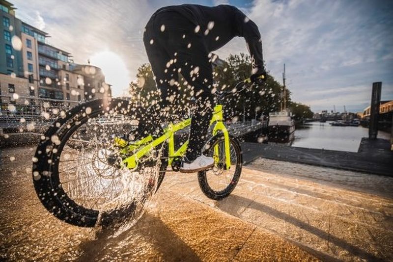 An action shot taken with a Canon Speedlite EL-1 shows a stunt rider cycling down stone steps, a spray of water droplets caught by the flash. 