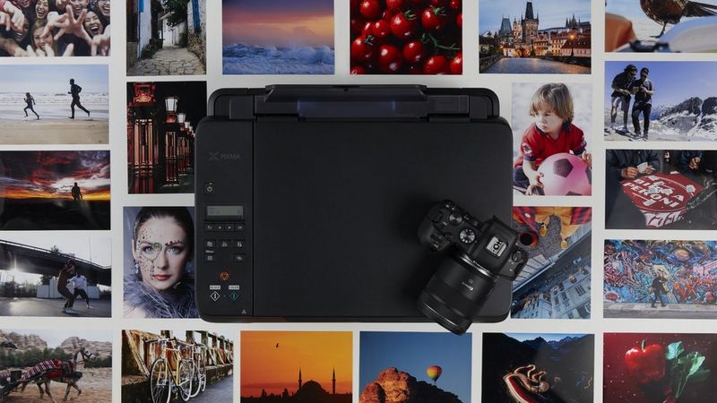 Eine Canon Kamera und ein Canon Drucker mit gedruckten Fotos im Hintergrund.
