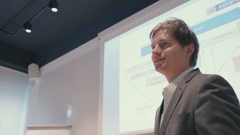 Man and woman look through a book printing catalogue at a large desk