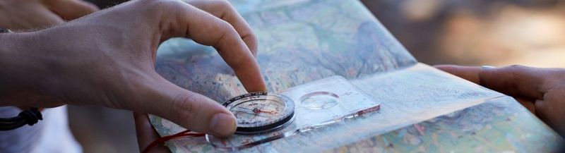 Hands, holding a compass over a map