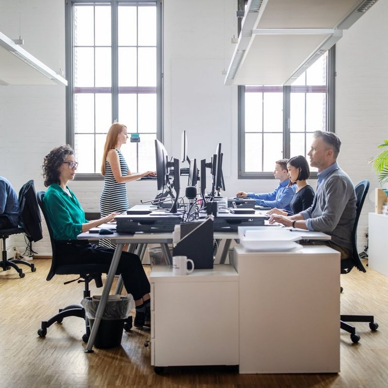 Colleagues work at their computers in a white office space