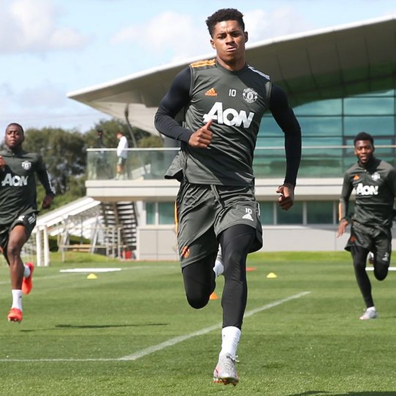 Three young footballers run across the pitch. They are wearing grey strips with AON printed on the front.