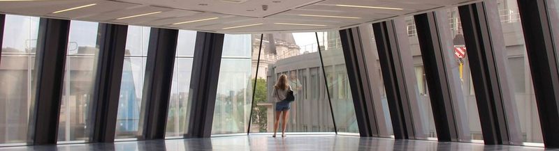 A woman with her back to the camera, standing on the floor of a glass office building