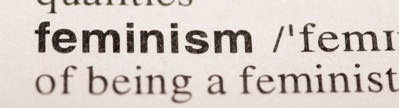 A close up photo of the dictionary definition of feminism. The words shown on the first lineare are ‘Feminism/’femi’. The second line shows the words ‘of being a feminist’.