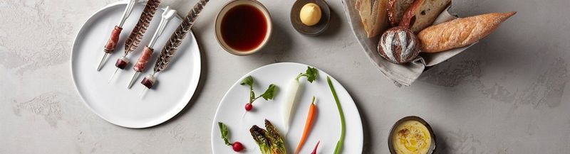 A selection of plates, beautifully arranged. Vegetables, meats and assorted bread.