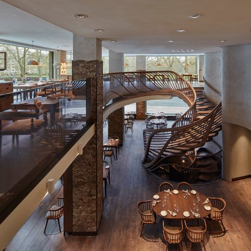 A wide view of the restaurant, showing the winding oak staircase against the floor to ceiling windows that overlook Green Park.
