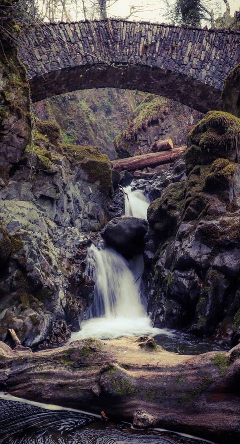 A fantastical waterfall under a bridge