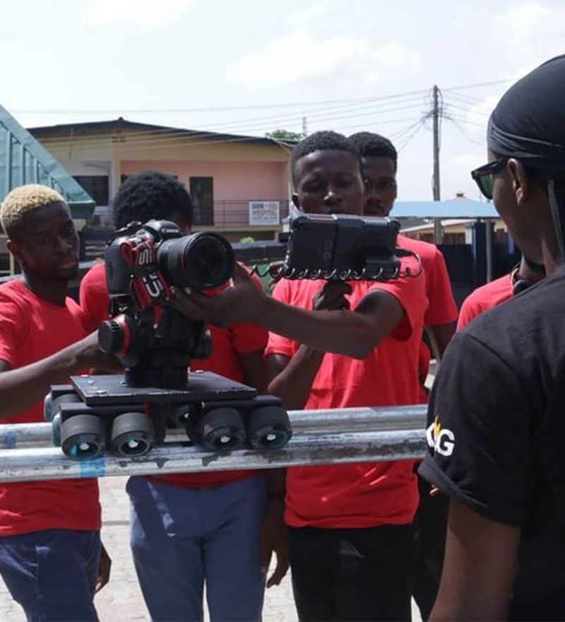 Several young men with a camera on a wheeled rig shoot a music video
