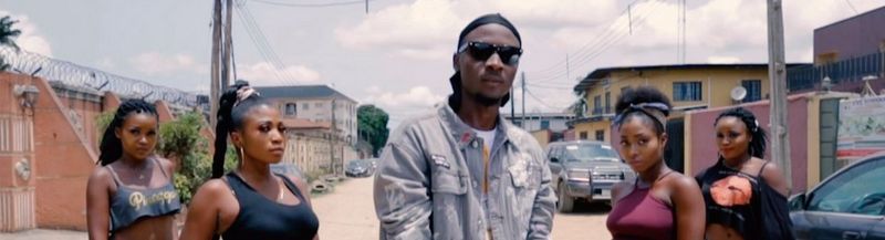 A young man in sunglasses with two young women on either side of him, standing on a Lagos street.