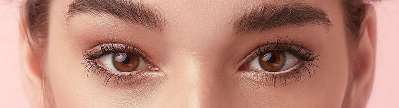 A close-up on a woman's eyes. They are brown and her make up is subtle shades of gold. She has fashionably natural eyebrows.