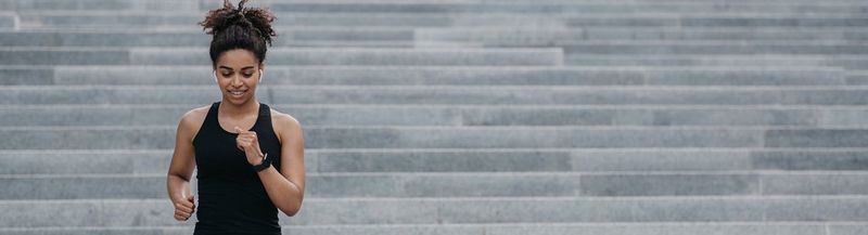 A woman in a black vest runs down a set of concrete steps