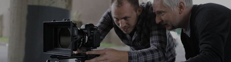 Two camera men inspecting the rear screen of a Canon EOS camera
