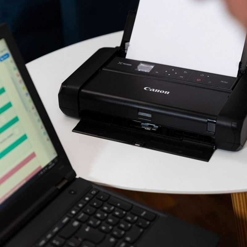 Canon PIXMA TR150 mobiler Tintenstrahldrucker mit Akku Auf einem Tisch neben einem Laptop