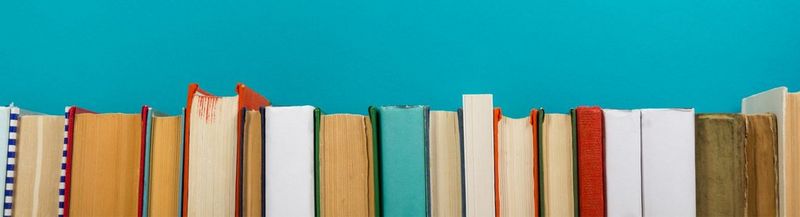 A man’s hands, holding a stack of books.