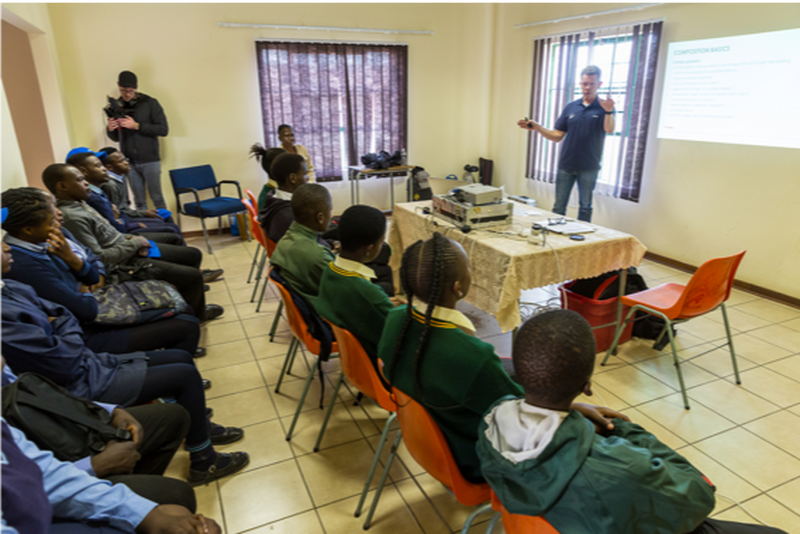 Students wearing purple baseball caps, head out on a game drive with their cameras