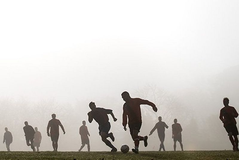 Footballers silhouetted against the early morning fog. 