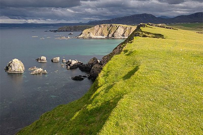 The sun shines through dark clouds at Faraid Head, Sutherland, Scotland, 2019. 