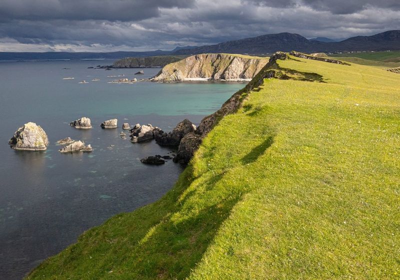The sun shines through dark clouds at Faraid Head, Sutherland, Scotland, 2019. 