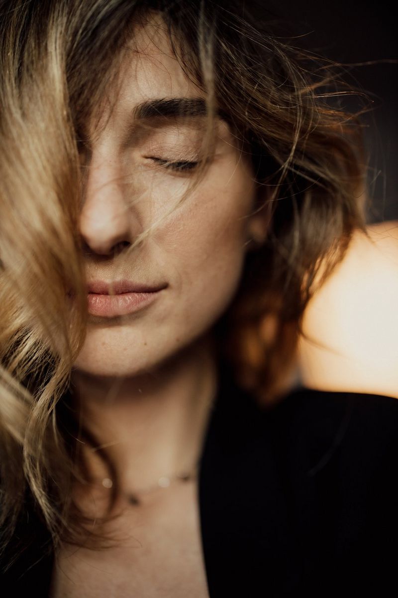 A self-portrait of Marina Karpiy with her eyes closed, her hair falling over her face.