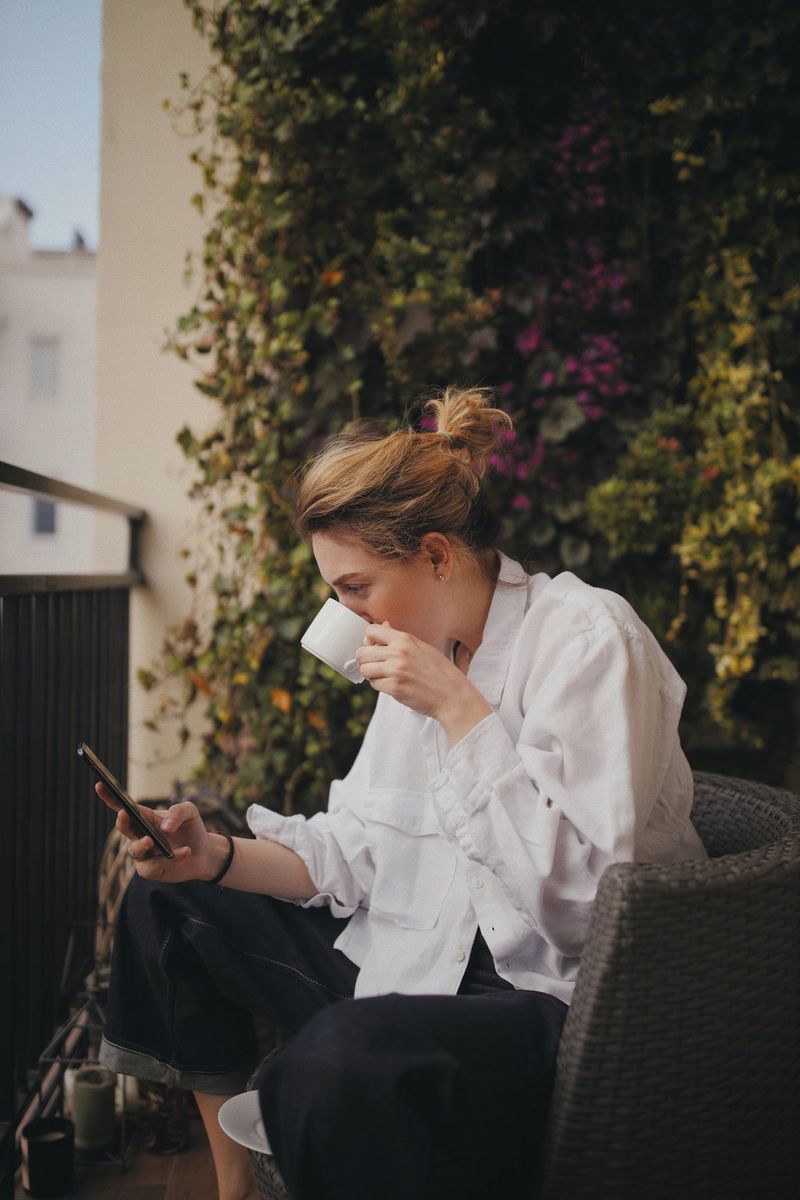 Marina Karpiy drinking a coffee while sat cross-legged on a chair in her garden.