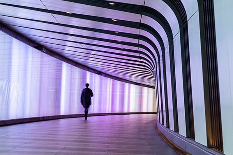 Person walks through pink lit corridor