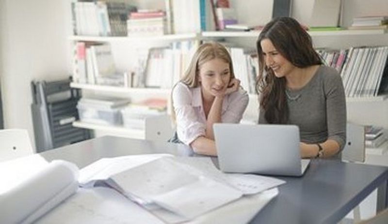To damer ser på en computer, der ligger en masse papir foran dem, de er ved at skabe effektive kampagner med målbar respons ved hjælp af Canons business værktøjer