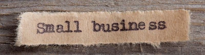 A ripped piece of brown paper with 'small business' typed on it, using a typewriter