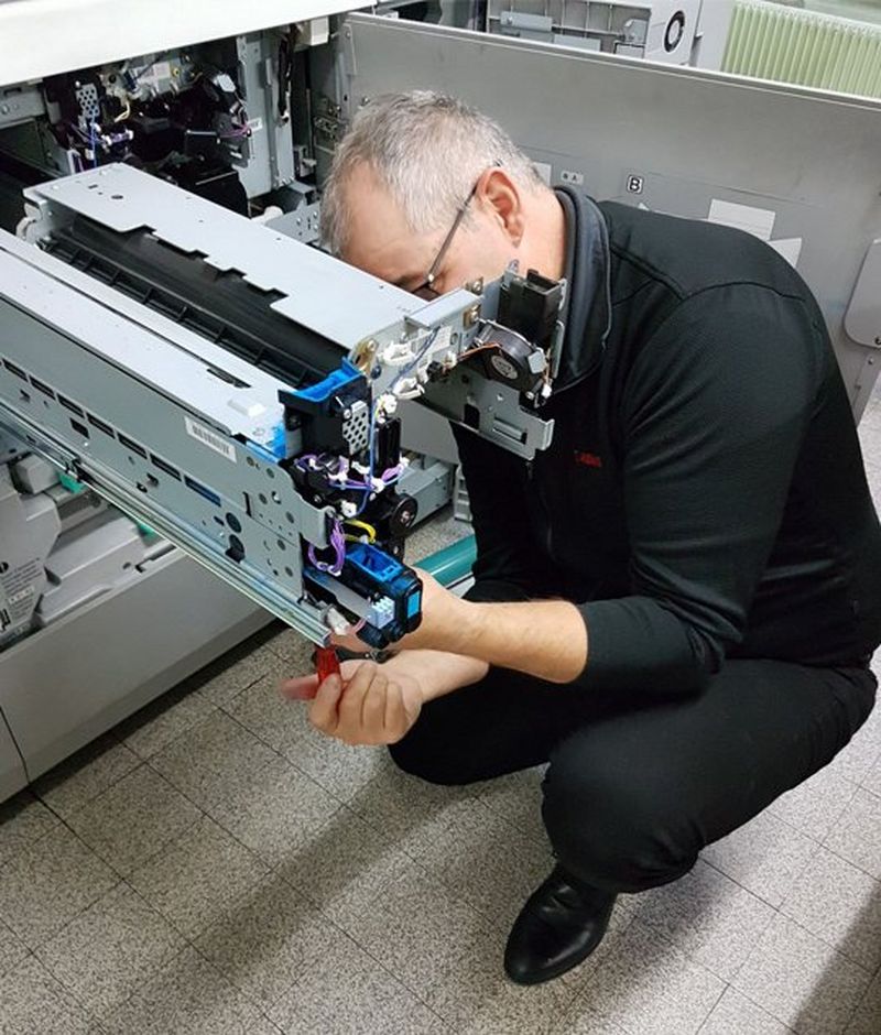 A Canon service engineer fixes the inside of a printer. 