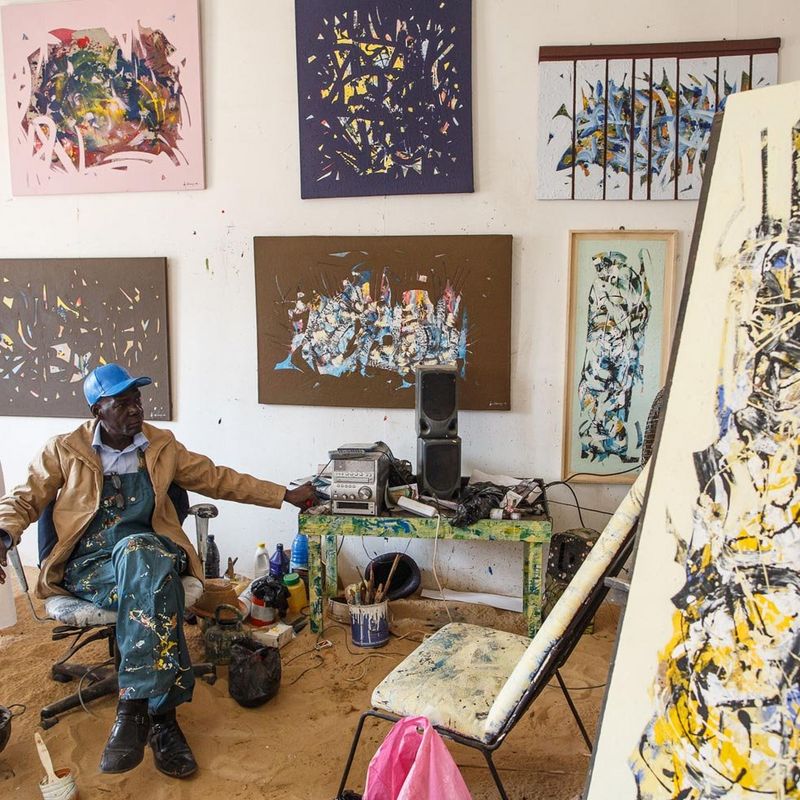 artist surrounded by his paintings