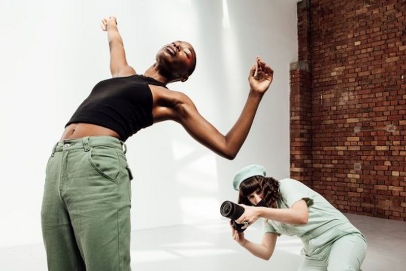 A model bends over backwards, her arms in the air, while photographer Eliška Sky crouches behind her to capture the shot.
