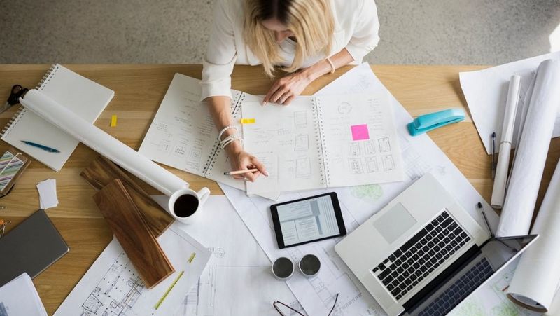 Top down designer drafting work at table