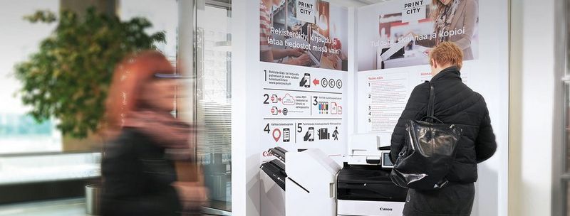 Woman looks at photo prints from a display on top of high speed inkjet press