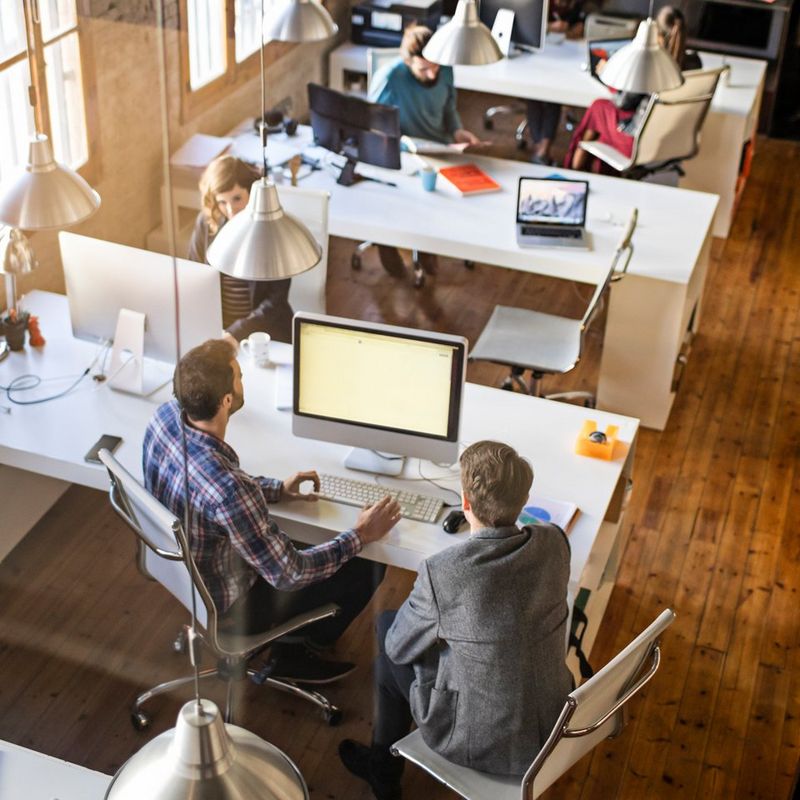 Two men sit working at a computer in an office