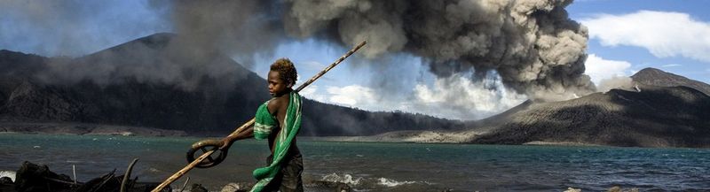 A pair of spectacles sat on top of paperwork, in front of a laptop and next to a phone