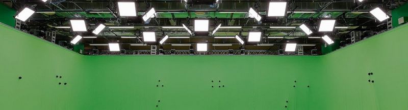 The ceiling and walls of the new Canon Volumetric Video studio in Kawasaki, Japan. The walls are green and have small, round black objects protruding from them at seemingly random positions and intervals. Above are more than two dozen flat square lights hanging from a rig below the ceiling.