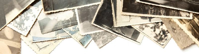 A selection of old black and white photos, spread across a white surface.