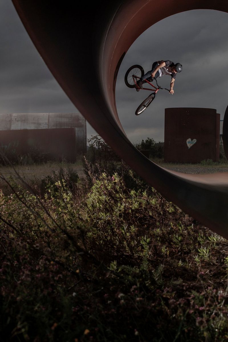 A BMX rider jumping off the inside of a large tube.