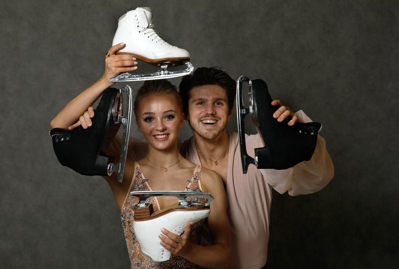 A male and female ice skater holding their ice skating boots. Photograph by Andrey Golovanov.