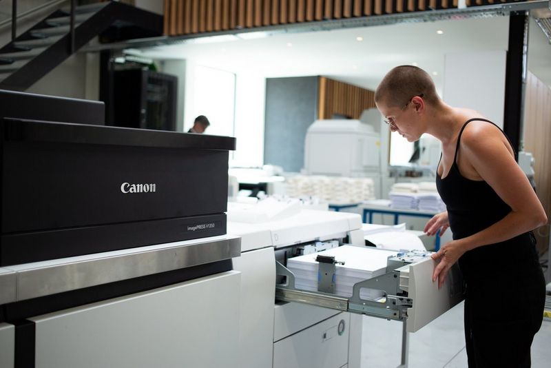 Female operator loading paper into media tray of digital press.